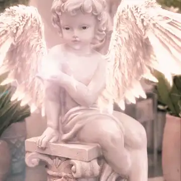 Animated GIF: Soft pink-lit cherub angel statue with feathered wings sitting on a pedestal.