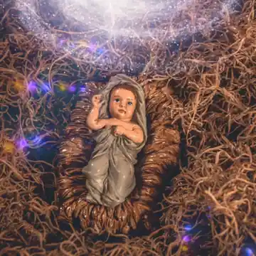 Animated GIF: Baby Jesus lying in a manger of straw under a glowing light.
